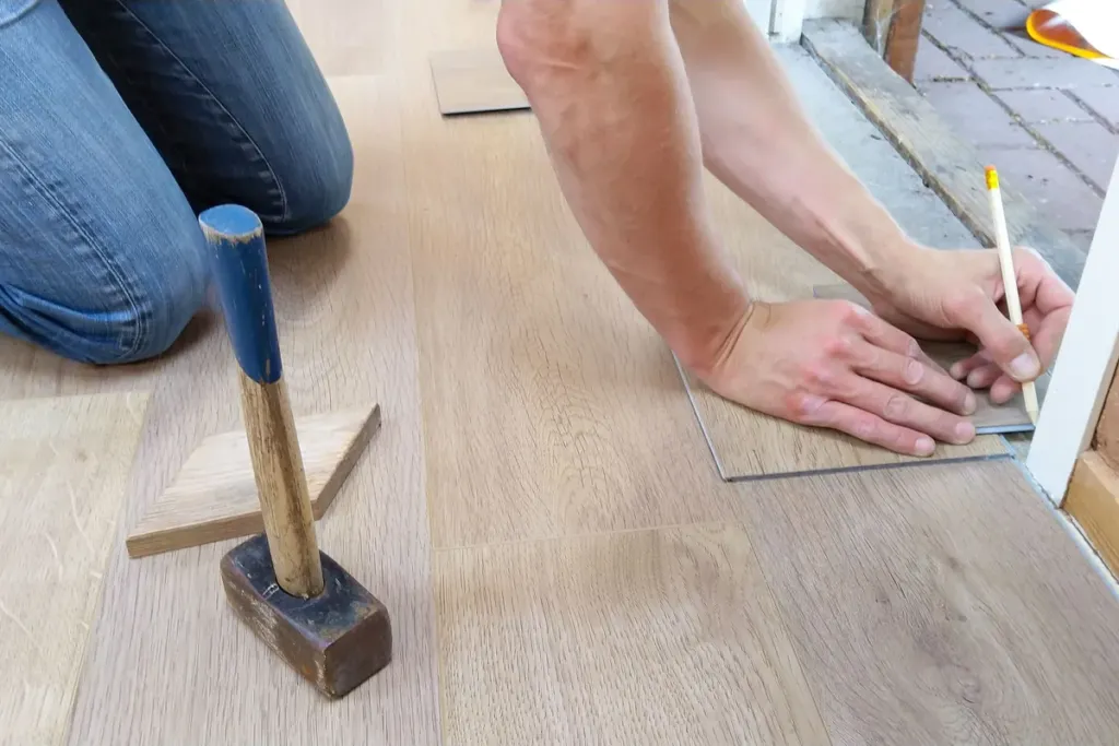 Klusser meet en markeert laminaatplanken af voordat hij de laatste rij op maat zaagt