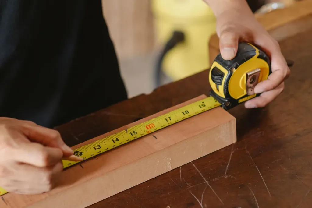 Timmerman meet een houten plank op de werkbank met een rolmaat voor het zagen